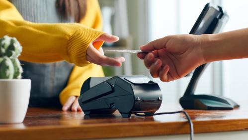 Two hands meeting over a payment terminal with one holding a credit card.