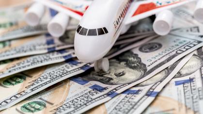 Toy jetliner sitting atop multiple US dollars.