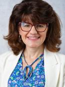 Headshot of Christina Dolce in a blue shirt and white shawl 