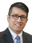 Headshot of Eduardo Valenzuela wearing glassing, a dark grey suit, and a blue tie. 