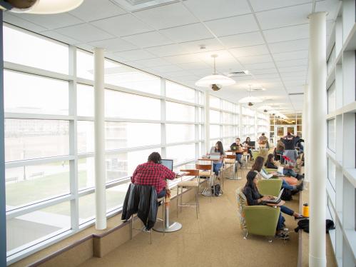 Students sit and study on laptops along sky bridge hallway of Livingston Student Center