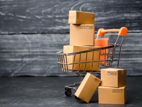 A miniaturized shopping cart filled with cardboard boxes.