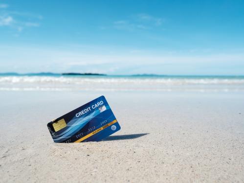 A blue credit card placed on a tropical beach
