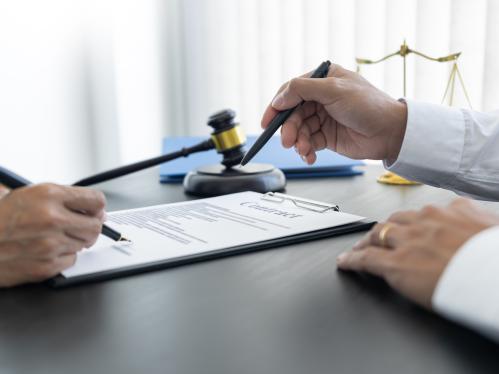 2 lawyers are discussing terms and condition, sitting in front of the scales of justice and a gavel.