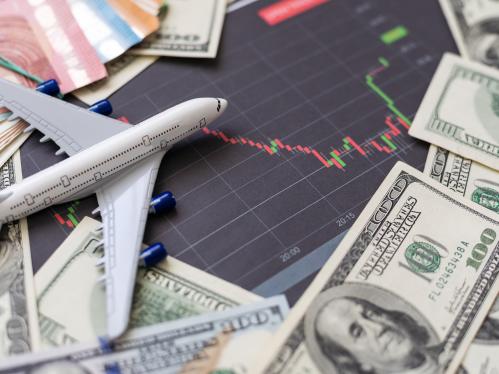 Toy airplane sitting one a red and green graph, surrounded by US dollars.